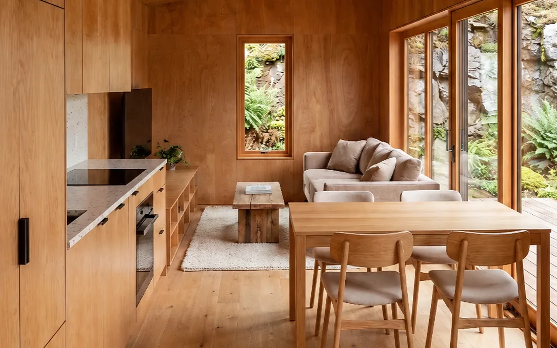 The Ledge interior, one room carrying kitchen, dining, and living toward the glazing