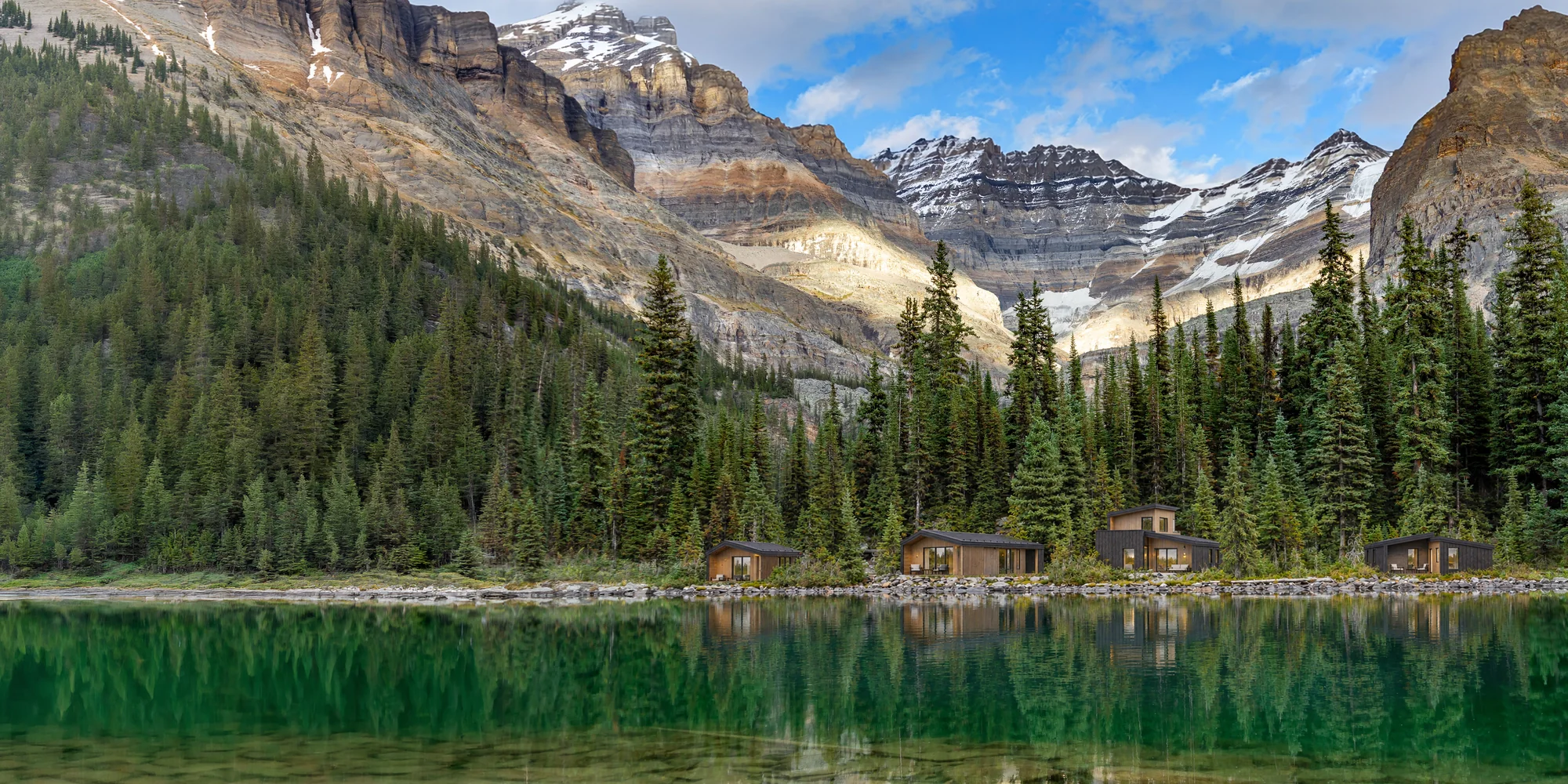 Four cabins along a lakeshore, mountains behind