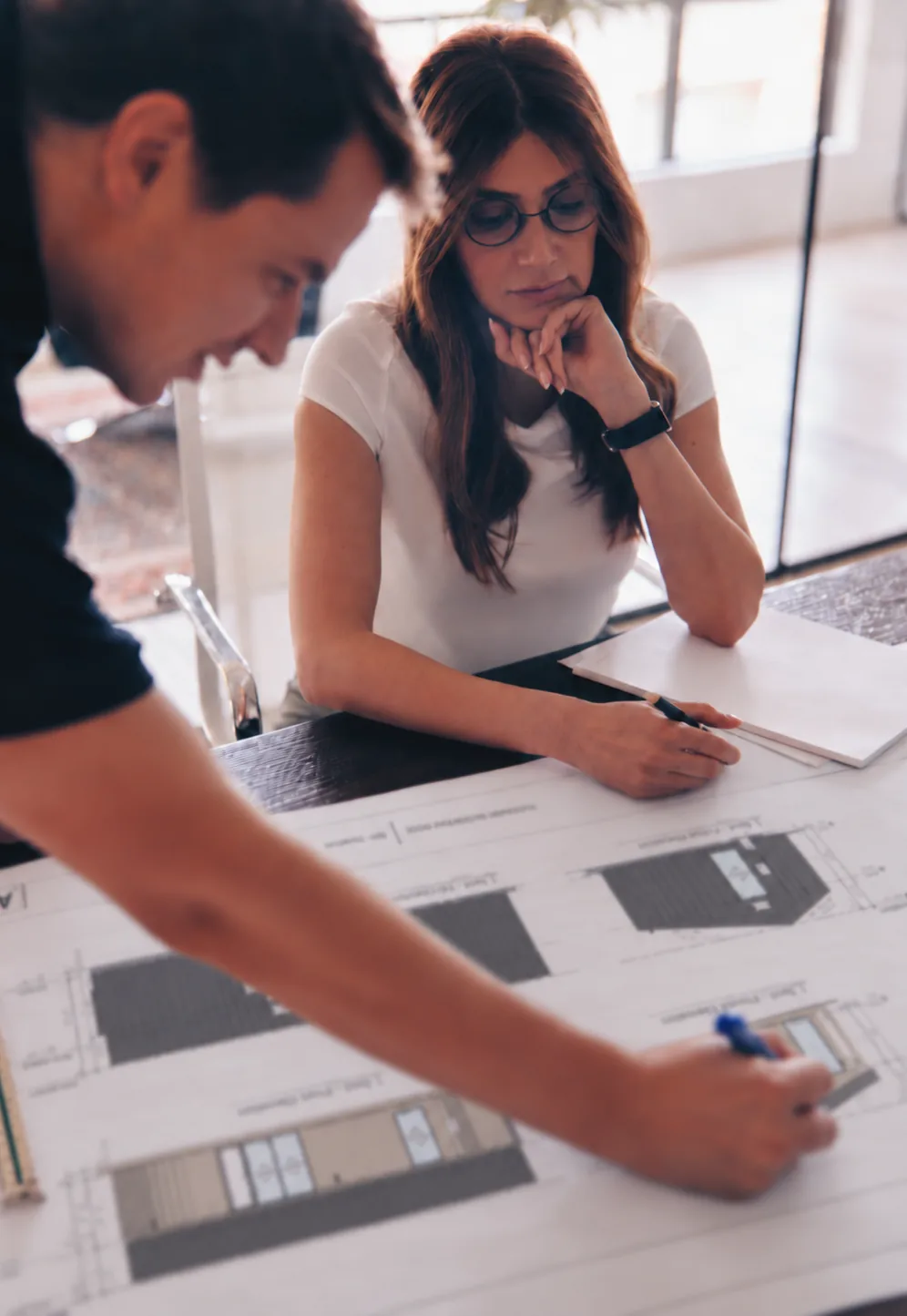Two Placemark designers reviewing cabin elevations on the table